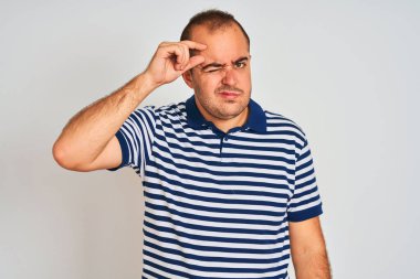 Sıradan çizgili polo giyen genç adam izole edilmiş beyaz arka planda dikiliyor. Alnındaki sivilceden mutsuz olduğunu gösteriyor. Siyah noktalı çirkin bir enfeksiyon. Sivilce ve deri problemi