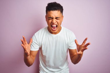 İzole edilmiş pembe arka planda dikilen Brezilyalı genç adam kollarını kaldırmış ve gözleri kapalı heyecanla haykırarak başarının çılgınlığını kutluyor. Kazanan konsept