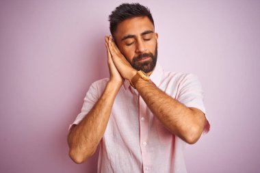 Genç Hintli bir adam rahat gömleğini giyer pembe arka planda dikilir uyur, yorgun düşler kurar, el ele poz verir ve gözleri kapalı gülümserdi..