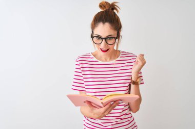 Güzel kızıl saçlı kadın pembe kitap okuyor beyaz arka planda gururla bağırıyor ve zaferi ve başarıyı kutluyor çok heyecanlı, coşkulu duygular içinde.