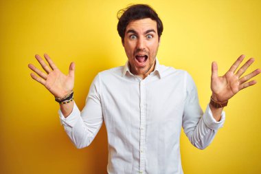 Zarif bir iş adamı, sarı arka planda dikilip kollarını kaldırıp heyecanla haykırarak çılgınca ve hayret verici başarısını kutluyor. Kazanan konsept