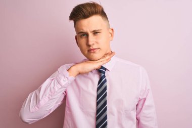 Gömlek ve kravat takan genç yakışıklı bir işadamı soyutlanmış pembe arka planda dikiliyor bıçakla boğazını kesiyor, saldırganlığı şiddetle tehdit ediyor.