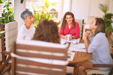 Genç ve güzel bir kız mutlu ve kendinden emin bir şekilde terasta oturmuş bir fincan kahve içiyor.