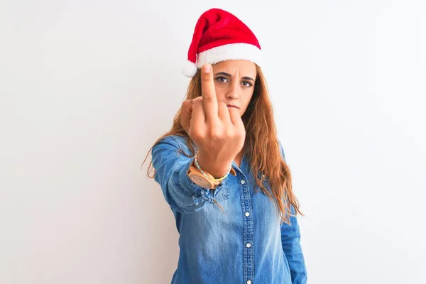 年轻美丽的红头发女人 头戴圣诞帽 背景孤寂 露出中指 举止粗鲁无礼 — 图库照片