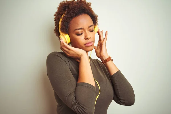Африканская Американка Наушниках Слушает Музыку Изолированном Фоне Серьезным Выражением Лица — стоковое фото