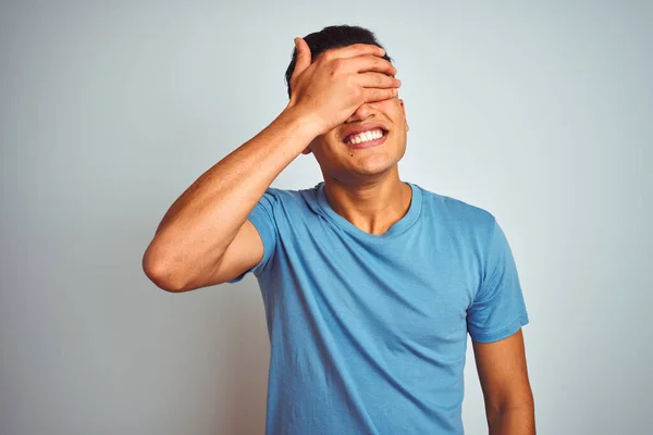 年轻的巴西男人穿着蓝色的T恤 站在孤立的白色背景上微笑着 满脸笑容 惊讶地捂着眼睛 盲目概念 — 图库照片