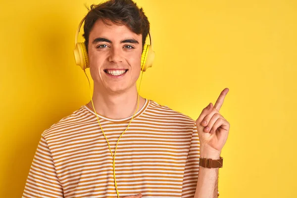 Menino Adolescente Usando Fones Ouvido Sobre Fundo Amarelo Isolado Com — Fotografia de Stock