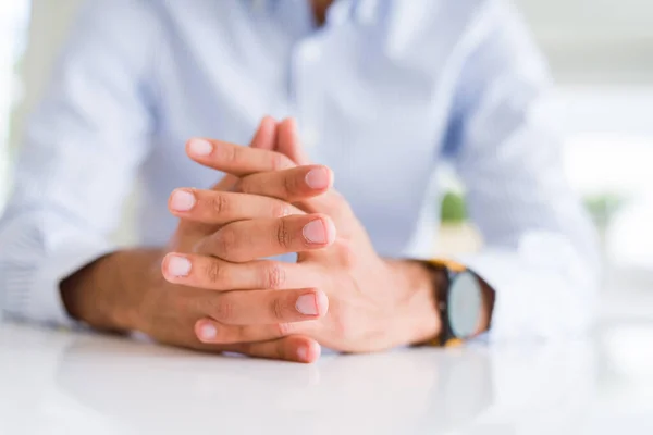 Primo piano dell'uomo con le mani incrociate sul tavolo bianco — Foto Stock