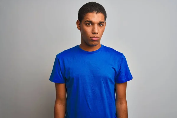 年轻英俊的阿拉伯男子穿着蓝色的T恤 站在孤立的白色背景之上 沮丧而忧心忡忡 愤怒而又害怕 悲伤的表情 — 图库照片
