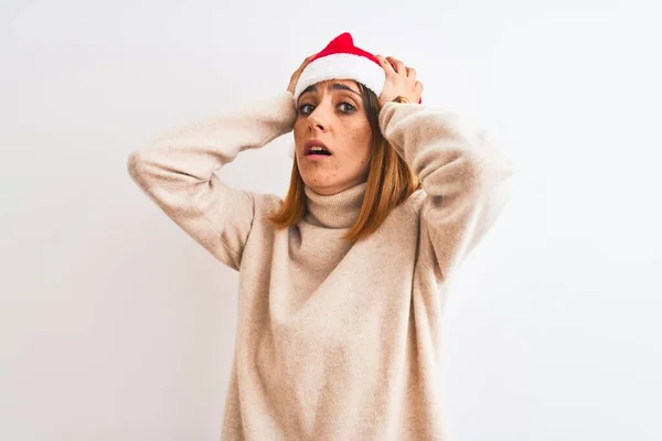 美しいです赤毛女性身に着けていますクリスマス帽子上の隔離された背景クレイジーと怖がっています手で頭 恐怖と驚きのショックでオープン口 — ストック写真