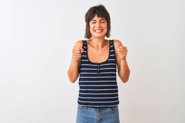 İzole edilmiş beyaz arka plan üzerinde duran çizgili tişört giyen genç ve güzel bir kadın başarının heyecanı içinde kolları havada ve gözleri kapalı zaferi kutlarken gülümsüyor. Kazanan konsept.