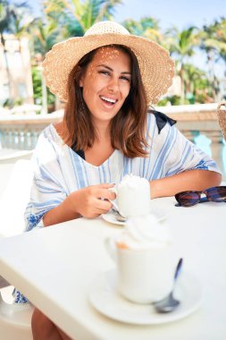 Güzel bir kadın otel otelinin barında oturmuş yaz tatilinde bir fincan kahve içiyor.