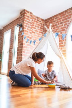Güzel öğretmen ve küçük çocuk yerde oturup anaokulunda içeride oynuyorlar.
