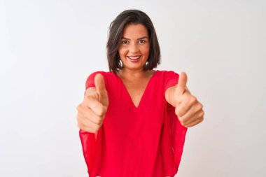 İzole edilmiş beyaz arka plan üzerinde kırmızı tişört giyen güzel bir kadın mutlu bir el hareketi yapıyor. Kameraya bakıp başarıyı gösteren ifade onaylanıyor.