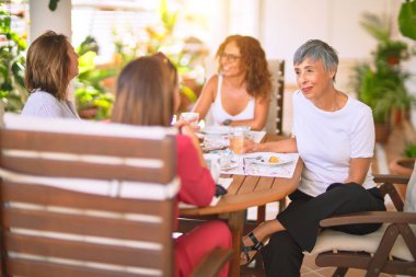 Genç ve güzel bir kız mutlu ve kendinden emin bir şekilde terasta oturmuş bir fincan kahve içiyor.