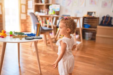 Renkli oyun odasında beyaz güzel bir bebek oyuncaklarla oynuyor. Anaokulunda mutlu ve şen şakrak.
