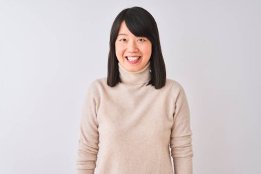 Genç, güzel, balıkçı yaka kazak giyen Çinli bir kadın izole edilmiş beyaz bir arka plan, yüzünde mutlu ve havalı bir gülümsemeyle. Şanslı kişi..