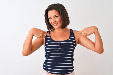 Mavi çizgili tişört giyen genç ve güzel bir kadın izole edilmiş beyaz arka planda duruyor. Yüzünde bir gülümsemeyle, gururlu ve mutlu bir şekilde kendini gösteriyor..