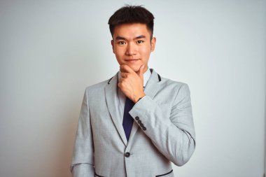 Asyalı Çinli işadamı takım elbise ve kravat takıp izole edilmiş sarı arka planda dikiliyor kameraya kollarını kavuşturup gülümseyerek bakıyor ve çenesini kaldırıyor. Olumlu düşünüyorum..