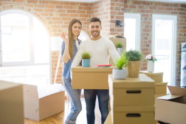 Genç çift yeni bir eve hareket, yeni dairenin anahtarlarını gösteren aşk sarılmak çok mutlu gülümseyen