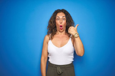 Orta yaşlı, kıvırcık saçlı, mavi izole edilmiş arka planda duran son sınıf öğrencisi bir kadın..