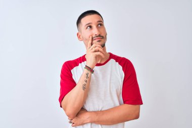 Soyutlanmış arka planda, elleri çenesinde soru soran, düşünceli bir genç adam. Düşünceli bir yüzle gülümsüyor. Şüphe kavramı.