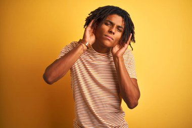 Sarı arka plan üzerinde duran çizgili tişörtlü Afro adam iki elini de kulak hareketi yaparken duymaya çalışıyor, dedikoduya meraklı. İşitme problemi, sağır