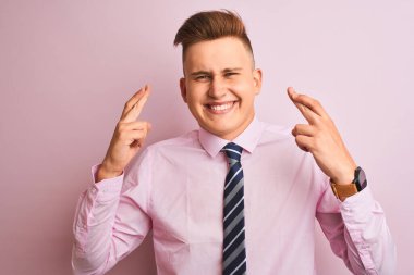 Genç yakışıklı işadamı gömlek giyen ve izole pembe arka plan gesturing parmak üzerinde duran umut ve gözleri kapalı gülümseyerek geçti. Şans ve batıl kavram.