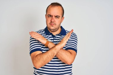 Sıradan çizgili polo giyen genç adam izole edilmiş beyaz arka planda duruyor. Reddedilme ifadesi kollarını kavuşturuyor. Negatif işaret veriyor, kızgın surat.
