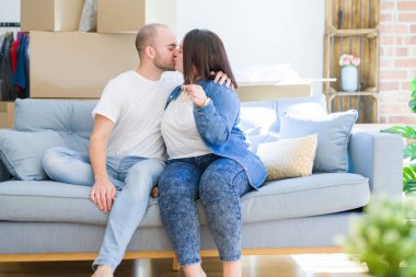 Kanepede oturan genç çift yeni ev anahtarlarını gösteren çok mutlu gülümseyerek, hareketli ve yeni apartmet kavramı satın