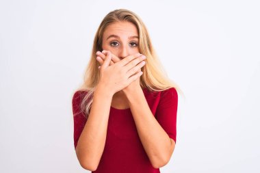 İzole beyaz arka plan üzerinde duran kırmızı t-shirt giyen genç güzel kadın hata için elleri ile ağız kapsayan şok. Gizli kavram.