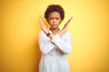 Afrika kökenli Amerikalı iş kadını, izole edilmiş sarı arka plan. Reddedilme ifadesi, kollarını kavuşturma, olumsuz işaret, kızgın surat.