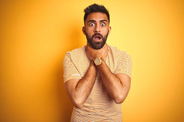 İzole edilmiş sarı arka planda duran tişörtlü genç Hintli adam boğularak öldü diye bağırıyor. Sağlık problemi. Boğulma ve intihar konsepti.