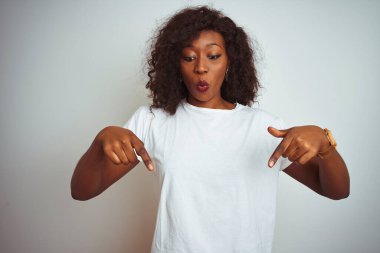 Genç Afro-Amerikalı kadın tişört giyiyor. İzole edilmiş beyaz arka plan üzerinde duruyor. İlan veren parmaklarıyla işaret ediyor.