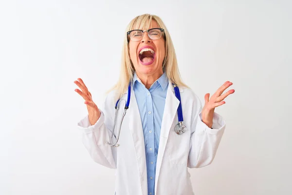 中年妇女医生 戴着眼镜和听诊器 站在孤独的白色背景上庆祝疯狂和疯狂的成功 胳膊抬起 闭上的眼睛兴奋地尖叫着 赢的概念 — 图库照片