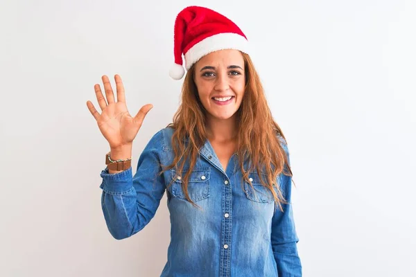 年轻美丽的红头发女人头戴圣诞帽 头戴孤零零的背景 带着五号手指 面带微笑 自信而快乐 — 图库照片