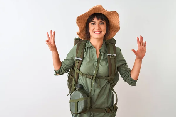 Hiker woman wearing backpack hat and water canteen over isolated white background showing and pointing up with fingers number eight while smiling confident and happy.