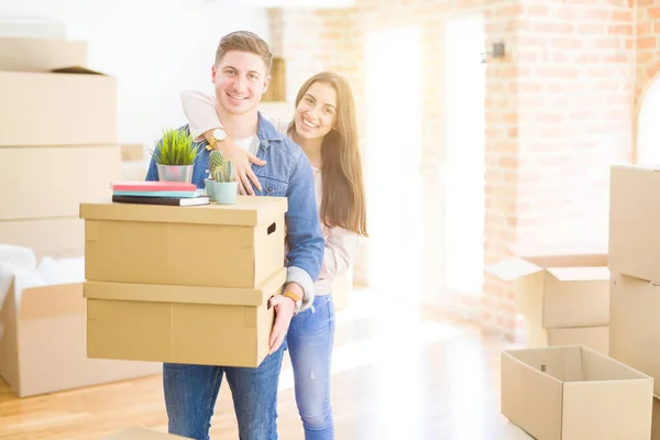 Hermosa pareja joven sonriendo en amor sosteniendo cajas de cartón , — Foto de Stock