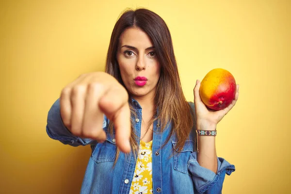 Young Beautiful Woman Eating Fresh Healthy Mango Yellow Background Pointing — Φωτογραφία Αρχείου