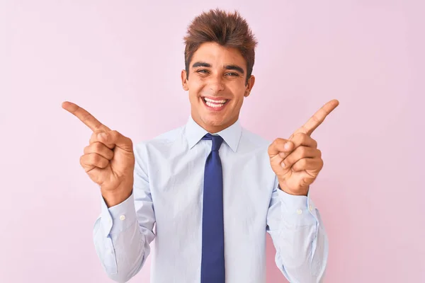 年轻英俊的商人穿着衬衫和领带站在孤立的粉红色背景微笑自信地用手指指向不同的方向 广告的复制空间 — 图库照片