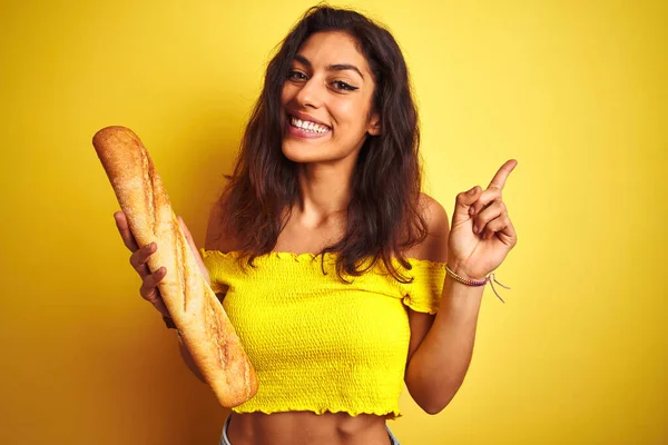 若いです美しいパンを保持パンスタンド上の隔離された黄色の背景非常に幸せなポインティングで手と指で側面 — ストック写真
