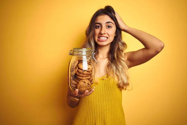 Young Beautiful Woman Holding Jar Cookies Yellow Isolated Background Stressed — ストック写真