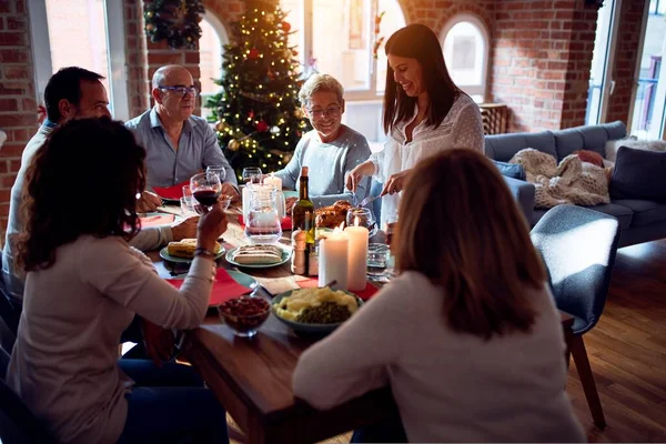 Family and friends dining at home celebrating christmas eve with traditional food and decoration, preparing turkey for dinner