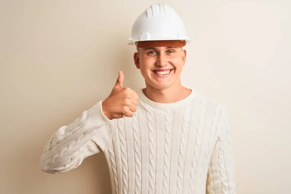 英俊的建筑师 戴着安全帽 站在孤独的白色背景上 手举着快乐的大拇指 用成功的表情看着摄像机 — 图库照片