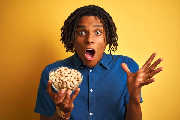 Joven Afroamericano Con Rastas Comiendo Pistachos Sobre Fondo Amarillo Aislado — Foto de Stock