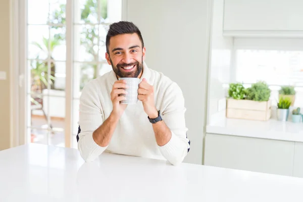 Hombre guapo sonriendo mientras disfruta bebiendo una taza de café en — Foto de Stock