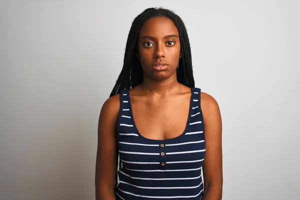年轻的非洲裔美国女人穿着条纹T恤 站在孤立的白色背景上 脸上有着严肃的表情 简单而自然地看着相机 — 图库照片