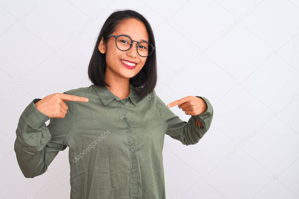 Young chinese woman wearing green shirt and glasses over isolated white background looking confident with smile on face, pointing oneself with fingers proud and happy.