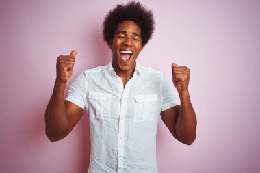 Afro saçlı, beyaz tişörtlü genç bir Amerikalı başarılı olmak için heyecanlı, kollarını kaldırmış ve gözleri kapalı zaferi kutluyor. Kazanan konsept.