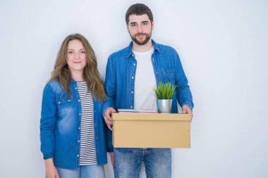 Genç bir çift ellerinde karton kutuyla beyaz izole arka planda yeni bir eve taşınıyor. Akıllı bir yüz ifadesiyle ciddi ciddi düşünüyor.